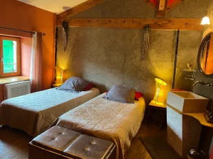 Chambre à thématique africaine de couleur grise et ocre avec disposition de deux lits simples.