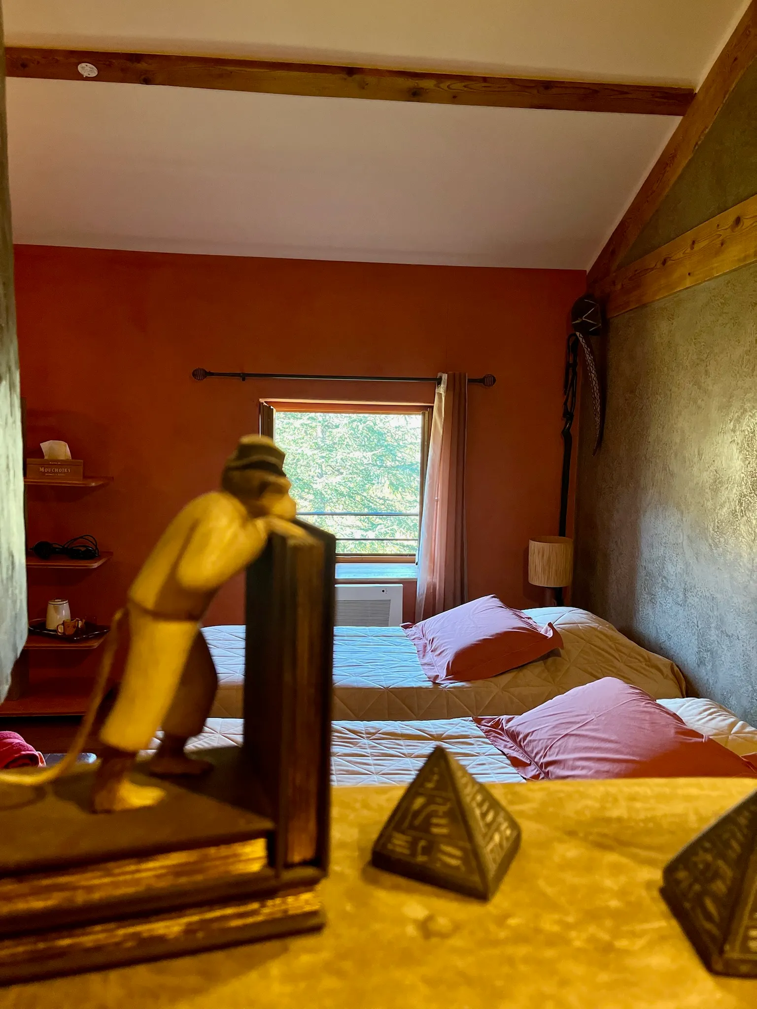 Afrikaanse kamer - Decoratie van de Afrikaanse kamer met bed op de achtergrond en zicht op de tuin