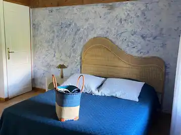 Habitación Criolla - Gran cama doble con cesta de toallas al pie de la cama y puerta del aseo al fondo