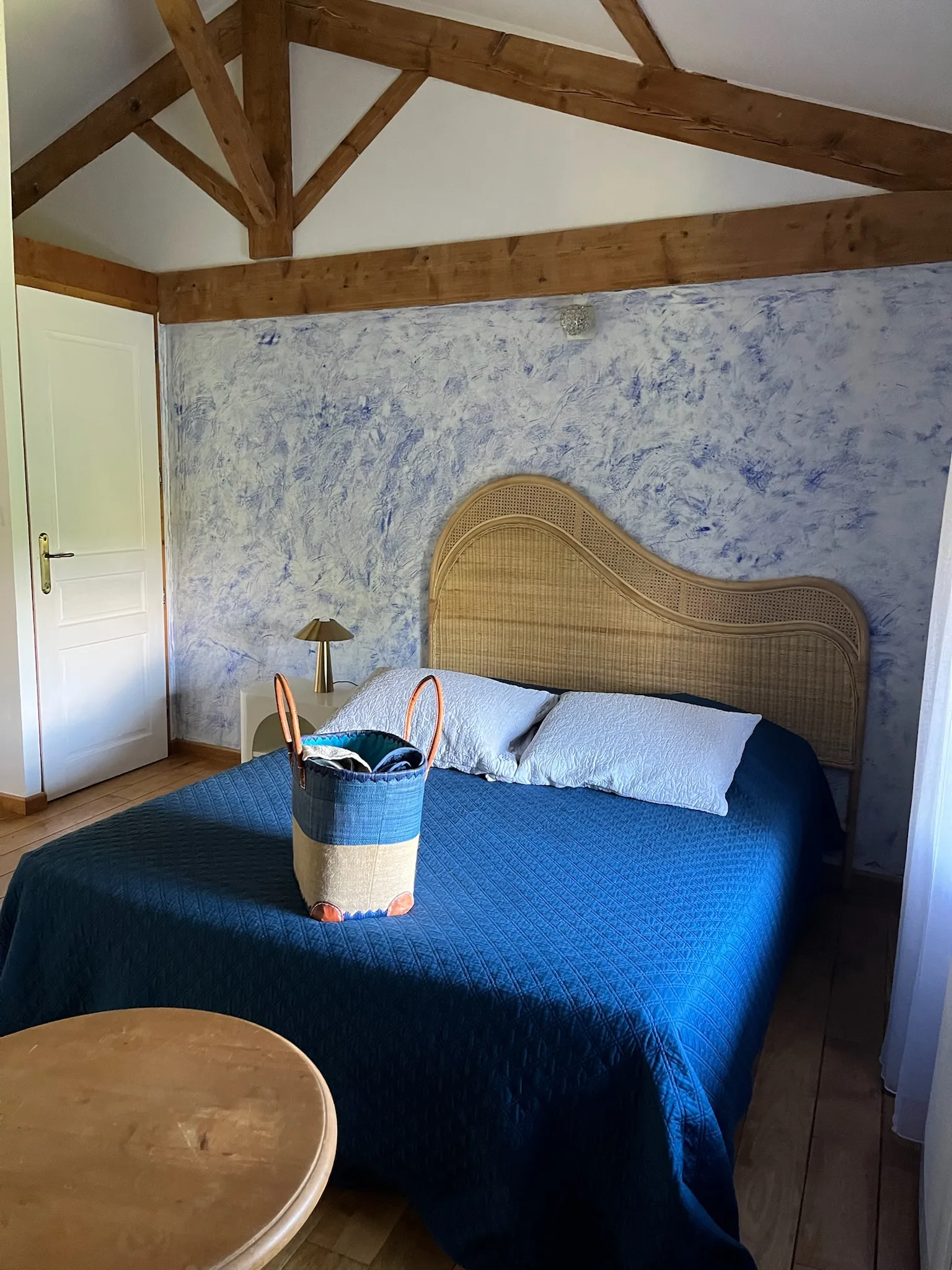 Habitación Criolla - Gran cama doble con cesta de toallas al pie de la cama y puerta del aseo al fondo