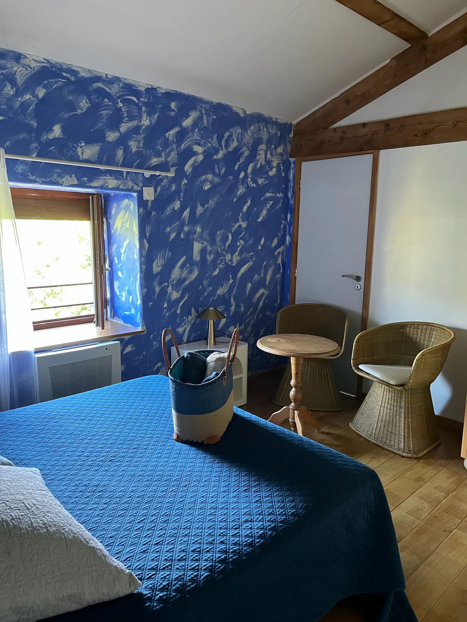 Habitación Criolla - Zona de escritorio de la habitación con toallas dispuestas sobre la cama y vista al jardín por la ventana