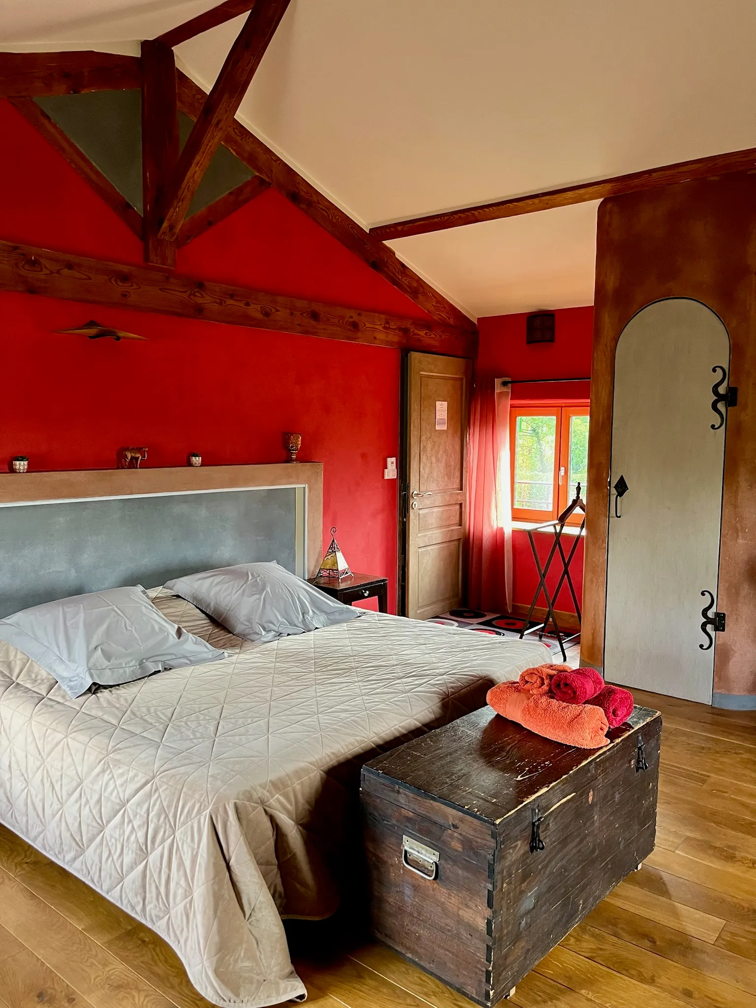Moroccan suite - Double bed seen from the side with bedroom door, courtyard window and towels arranged on the chest at the foot of the bed