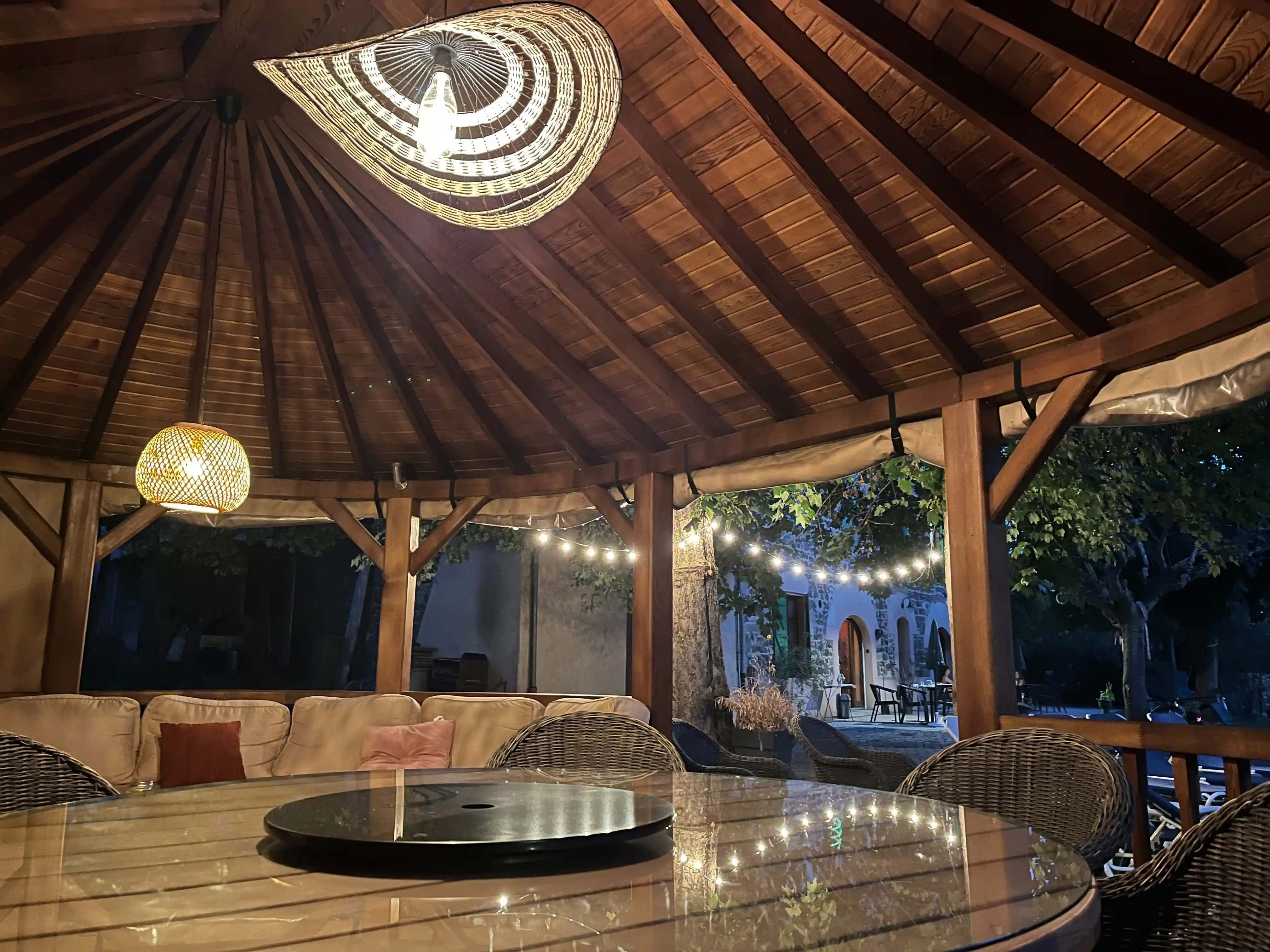 Paviljoen bij het zwembad met grote tafel en loungeruimte verlicht door lichtsnoeren