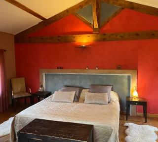 Chambre thématique marocaine. Aux couleurs rouge, ocre et gris. Nous voyons un lit king size recouvert d'un beau dessus-de-lit couleur or.