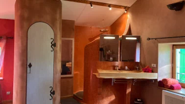 Photo d'une chambre sur laquelle nous voyons l'espace douche, double vasque et la porte des toilettes
