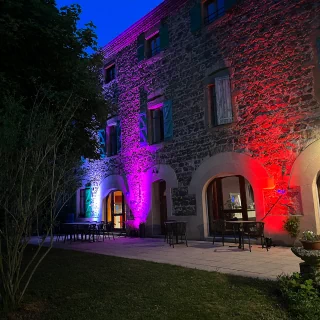 Vue de nuit de la façade avant de la maison illuminée par spots de couleurs.